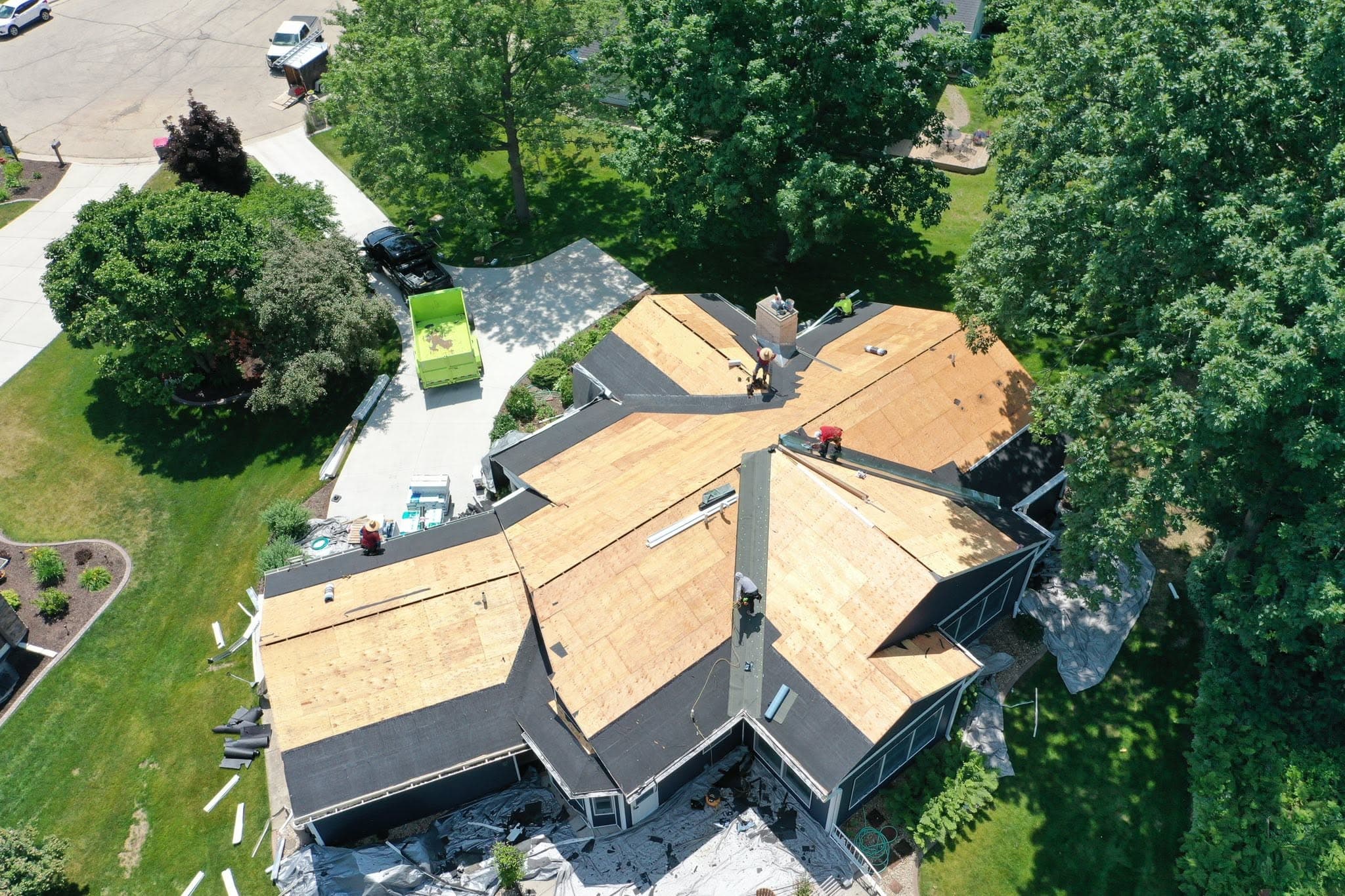 Aerial view of a residential roof replacement with sections of deck and underlayment visible