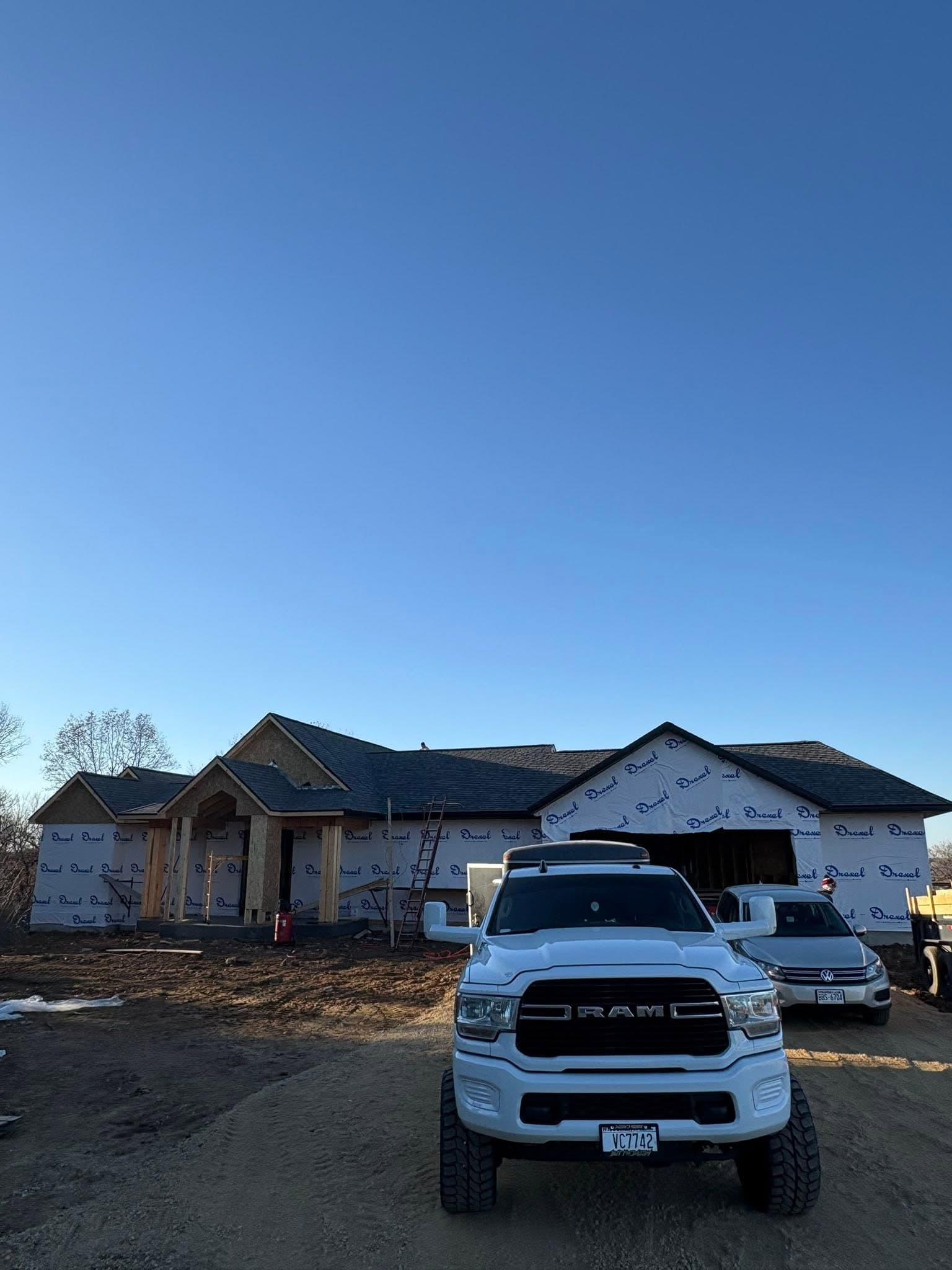Dark shingle roof above a residence with exposed exterior framing