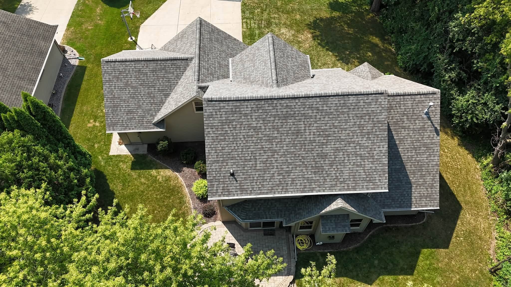 Side drone view of a completed gray shingle roof replacement