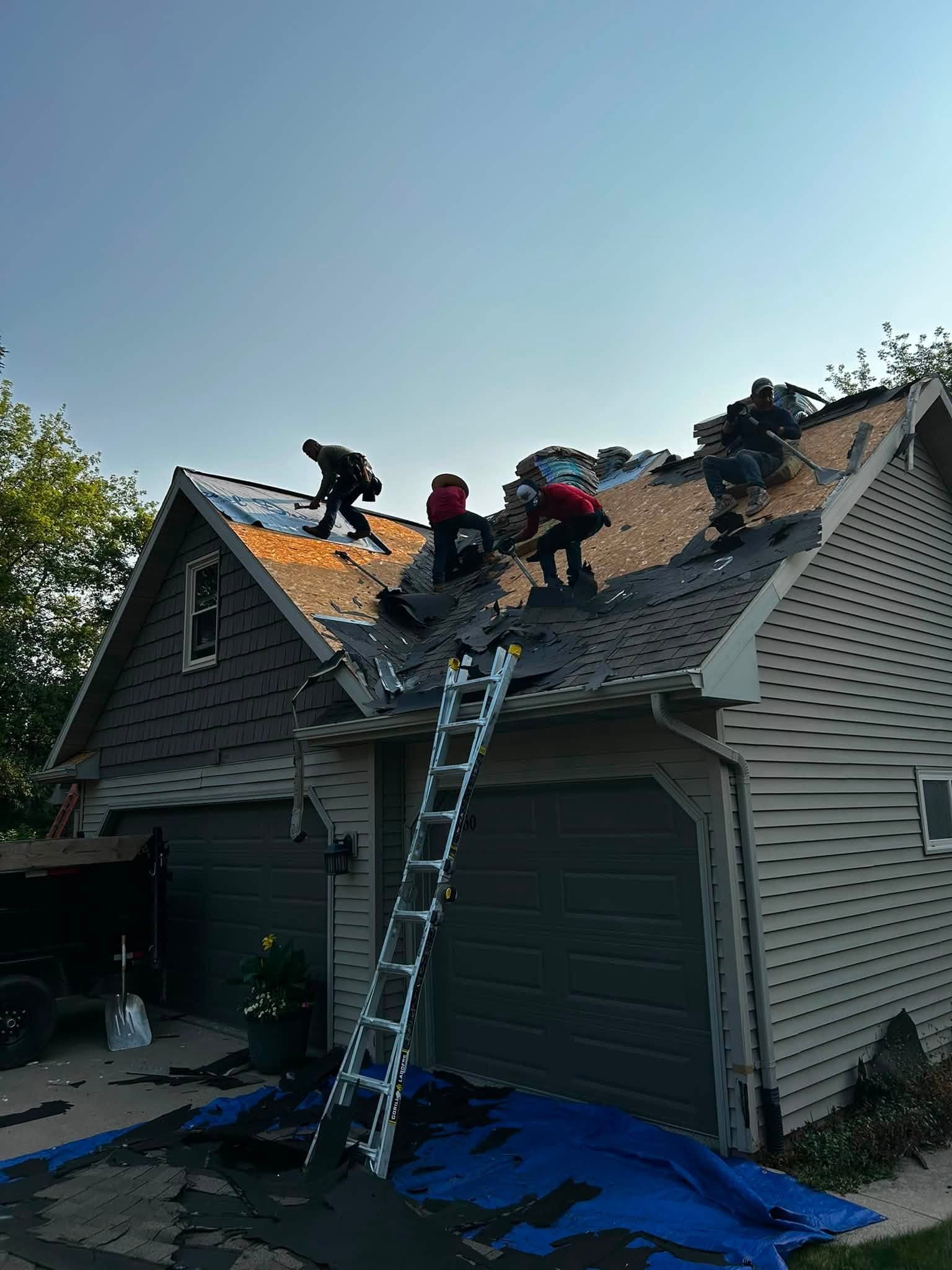 CM Roofing crew removing existing shingles during an active roof replacement