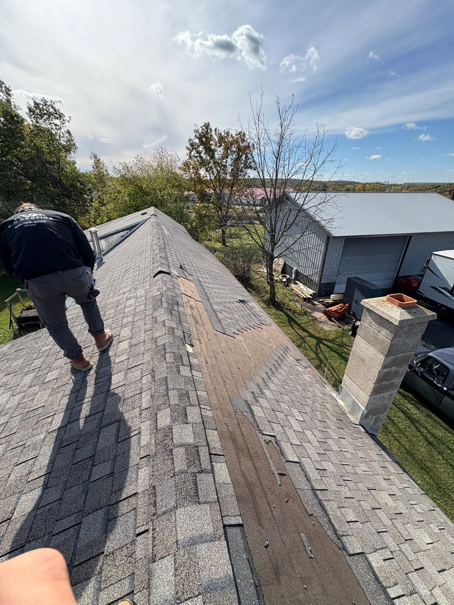 Roofer reviewing a long exposed strip where shingles are missing