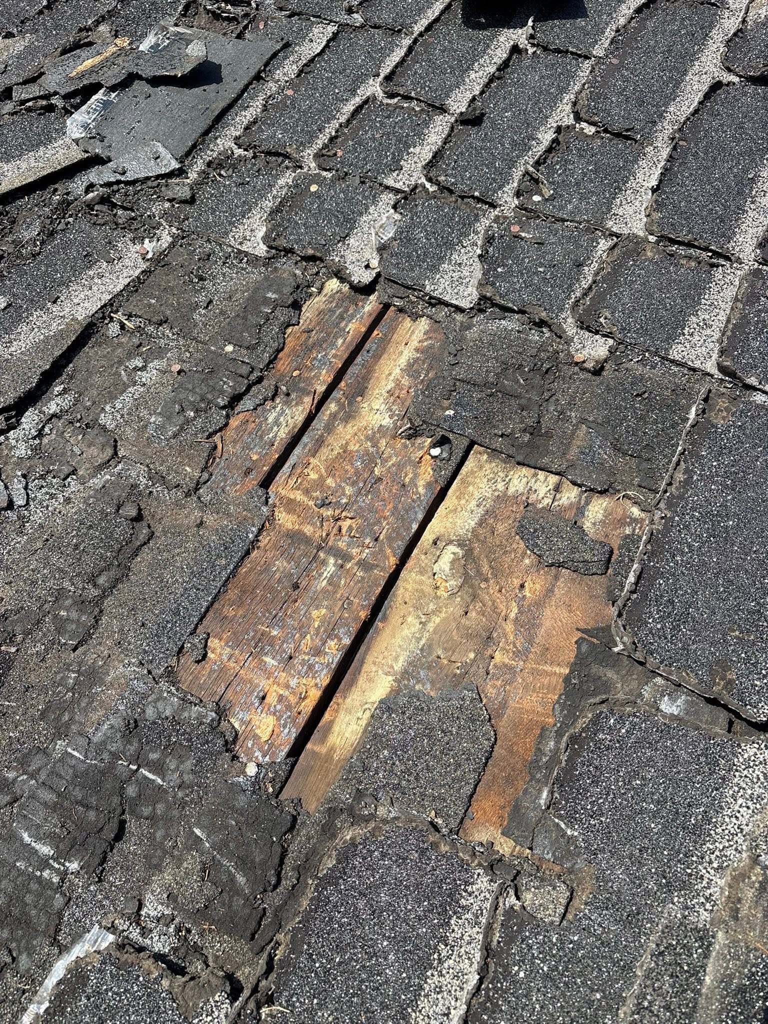 Deteriorated wood roof decking exposed beneath removed shingles